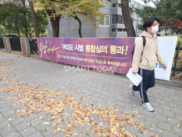 한 학생이 대우건설 플랜카드가 걸린 시범아파트 입구 일대를 지나고 있다. 출처=김종현 기자